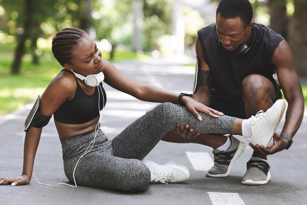 friend helping young jogger with hurt leg urgent care situation
