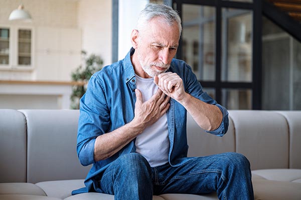 A man sitting down with shortness of breath and coughing