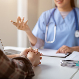 Woman provider speaking with patient while sitting at table.