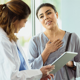 a woman with her hand on her heart, relieved that her diagnosis is not cancer