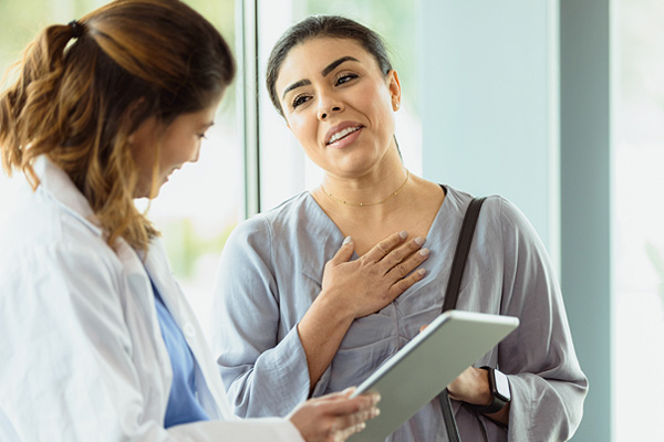 a woman with her hand on her heart, relieved that her diagnosis is not cancer