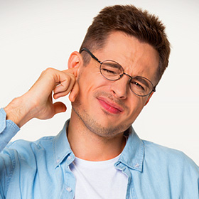 a man with his finger in his ear to try to stop the ringing from tinnitus