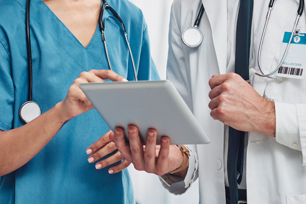 a nurse pointing at a tablet that a doctor is holding