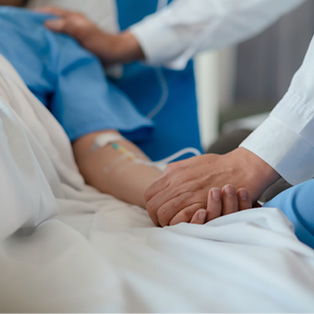 a patient in a hospital bed and a doctor by the bedside holding their hand