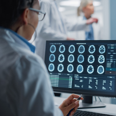 a neurocritical care surgeon looking at brain scans on a computer screen
