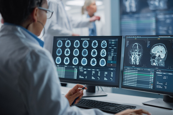 a neurocritical care surgeon looking at brain scans on a computer screen