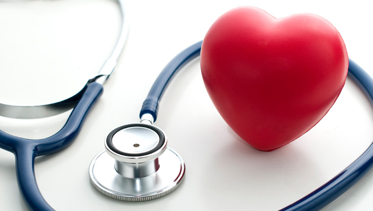 A stethoscope wrapped around a red heart-shaped stress ball