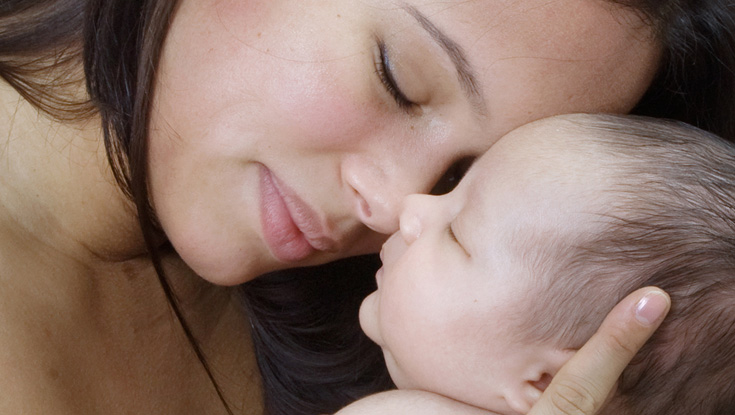 A woman snuggling her newborn baby, nose to nose