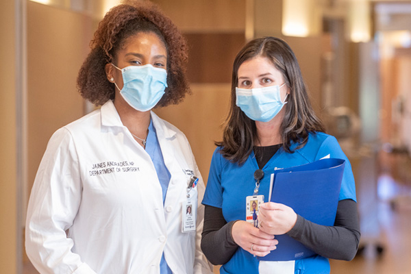 nursing colleagues standing side by side in a hospital hallway wearing masks