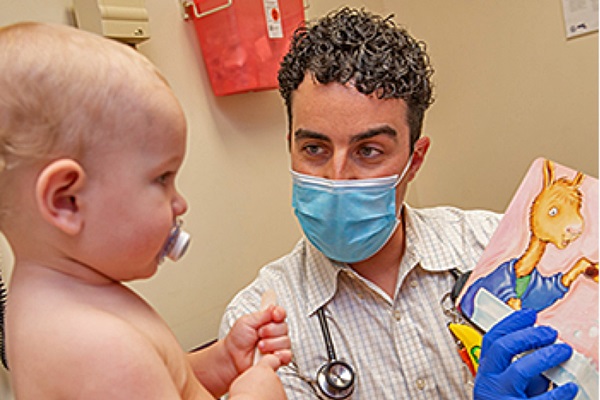 doctor showing a children's book to a baby