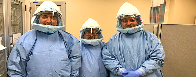 three infectious disease fellows in full body PPE in a hospital setting