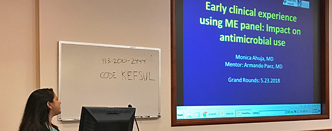 Candid photo of Infectious disease fellow presenting a slide introducing the impact of antimicrobials