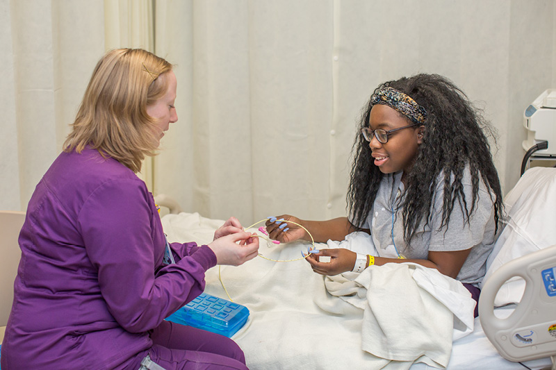 nurse showing a child patient how to bead