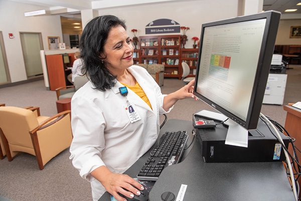 dr gladys fernandez working on a computer in the baystate library