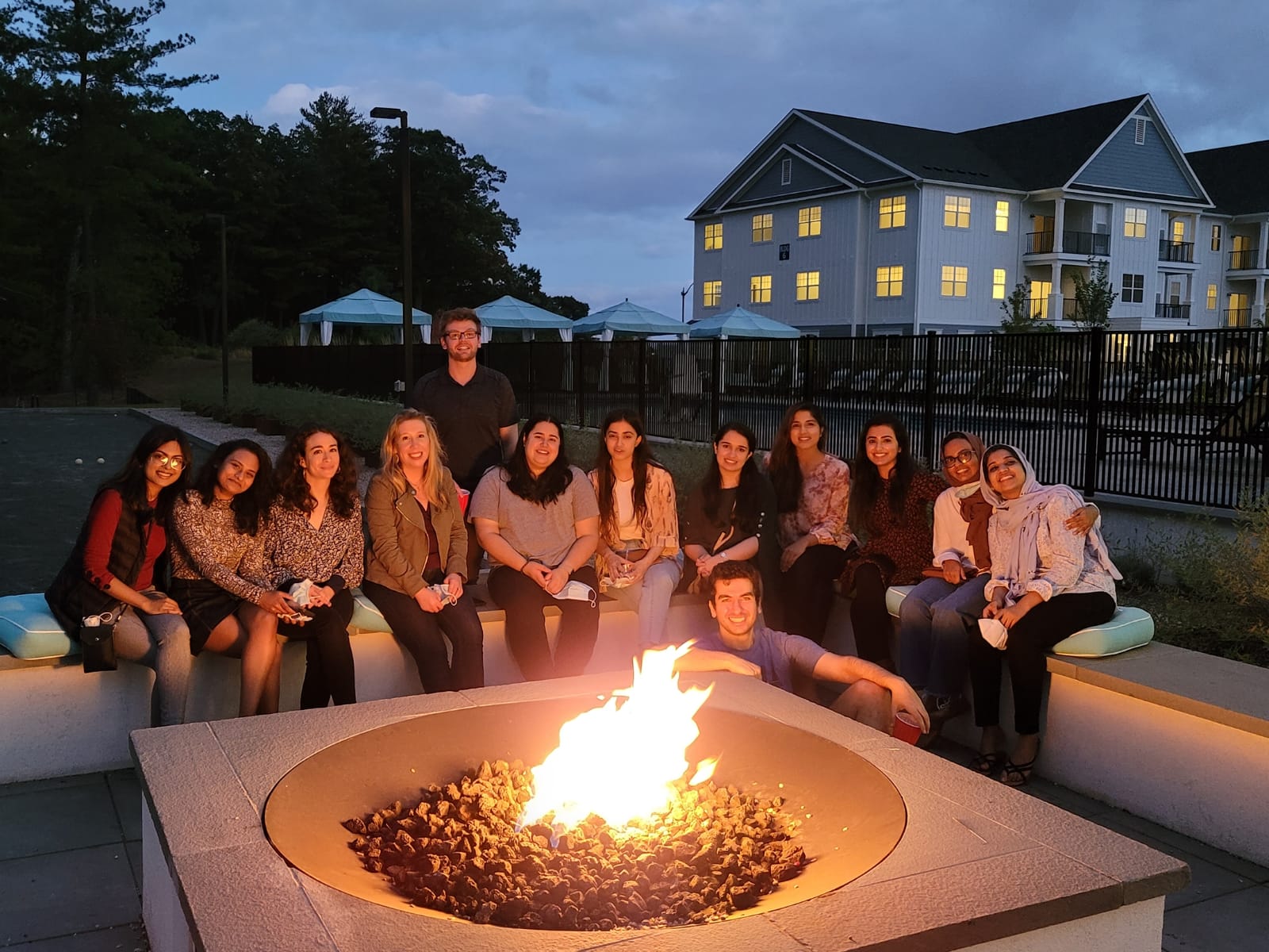 Outdoor nighttime group photo of internal medicine residents sitting around a fire
