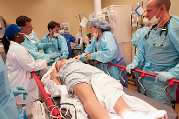 medical students surrounding a simulation patient 