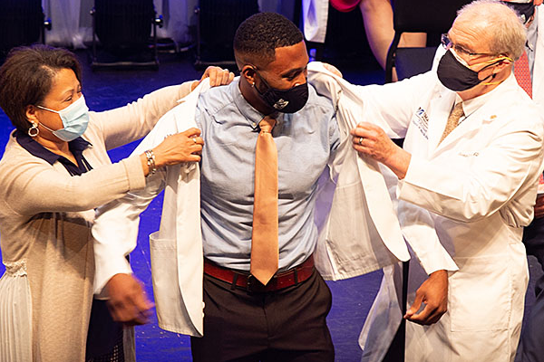 Kareem Nunnally Rivera donning a whitecoat on stage