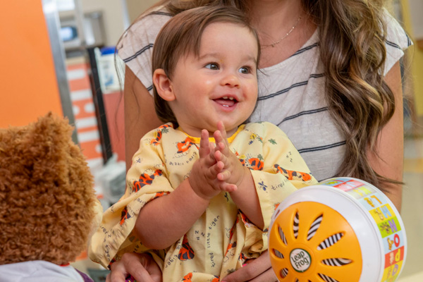 a toddler in a hospital johnnie playing with toys