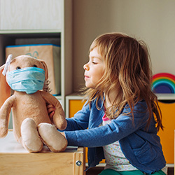 child and stuffed animal wearing face mask