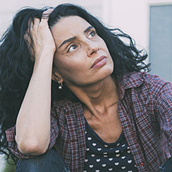 woman sitting on front steps deep in thought or worried