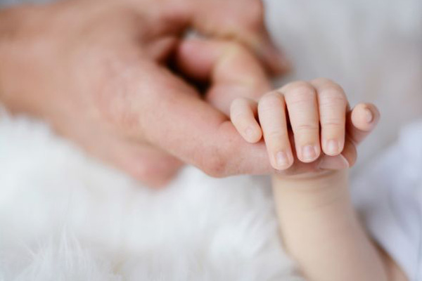 a closeup of a newborn babys hand clenching onto an adult finger