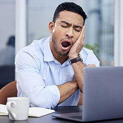 Man yawning at his computer