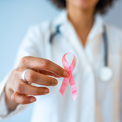 Doctor holds up pink ribbon symbolizing breast cancer awareness