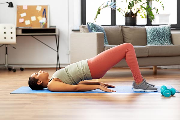 A woman on a yoga mat performing a bridge pose