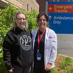 Alicenne standing next to Kristina Grochowski, both smiling in front of Ambulance Only and Emergency Trauma sign.