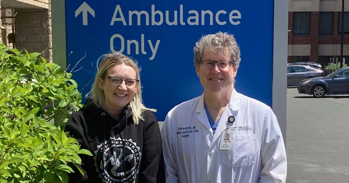 Alicenne and Dr. Kelly smiling, standing side by side in front of ambulance only sign