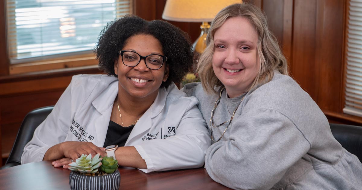 Julie Merritt and Dr. Tashanna Myers sitting close together at table while smiling 