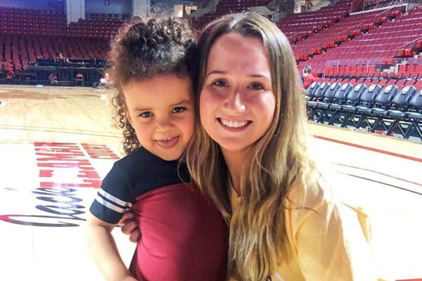 a child and mom posing together on a basketball court