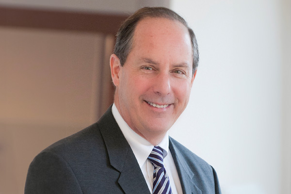 a man in a suit and tie smiling for the camera