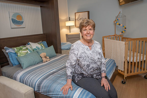Founder of Alicia's Angels, Jona Sager, sits on a bed in the Family Care Room in the Davis NICU at Baystate Medical Center.