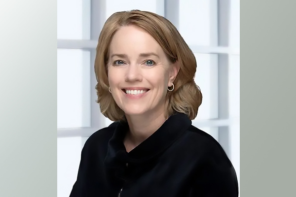 a woman with shoulder-length blonde hair wearing a black shirt and smiling for the camera