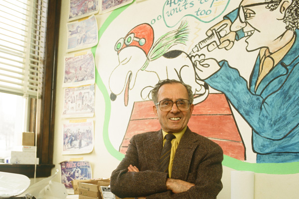 dr emil ferries with arms crossed in front of mural
