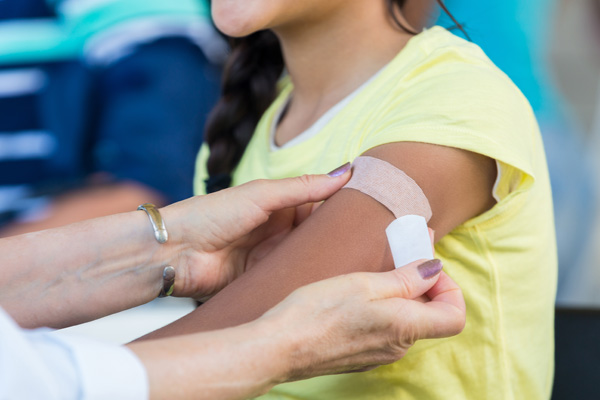 doctor putting on bandage after giving a vaccine to young girl