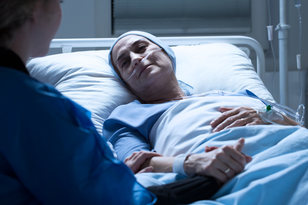 A hospital care giver holding a sick woman’s hand in the hospital.