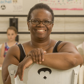 a dance teacher smiling with child dancers behind her
