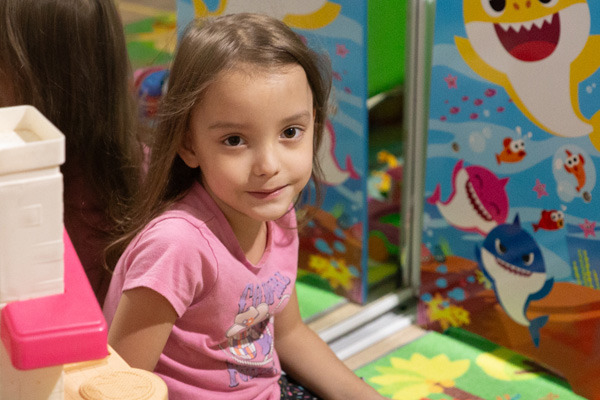 Elariya sitting amongst some toys and Baby Shark decorations