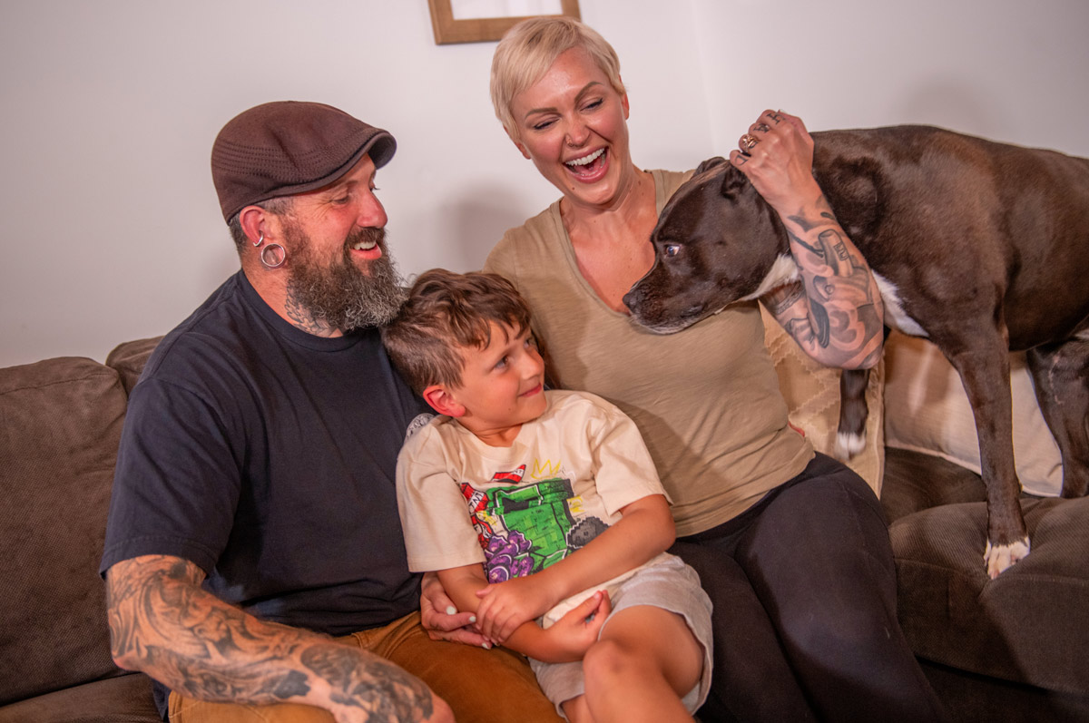 Jenn sitting on the couch with her family and her dog