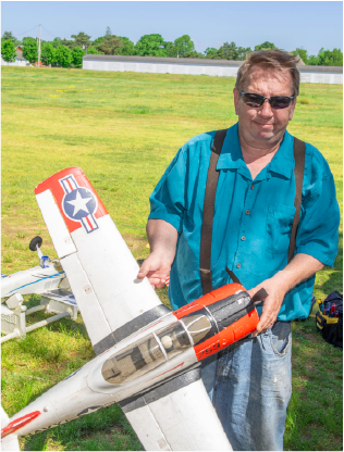 Man outside, smiling and holding model airplane.
