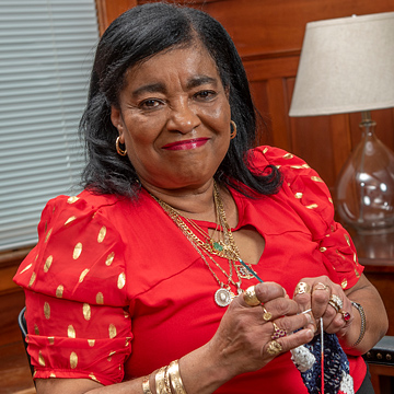 Yvonne Scott smiling with mouth closed while crocheting
