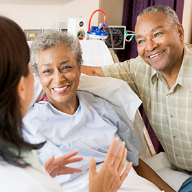 a doctor talking to a smiling patient and a smiling visitor