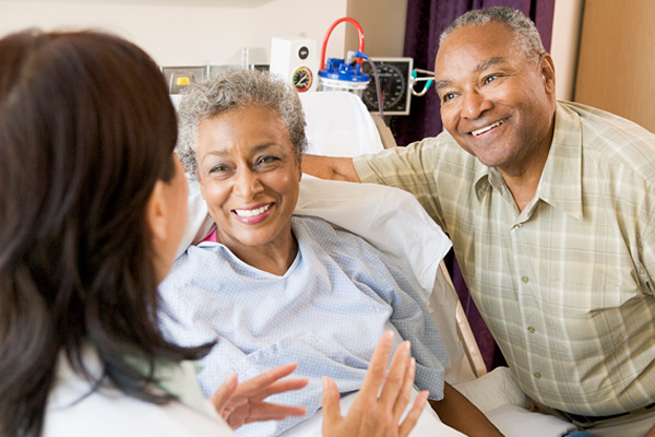 a doctor talking to a smiling patient and a smiling visitor