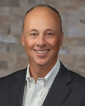 a man wearing a white button-down shirt and dark suit jacket smiling for the camera