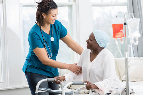a nurse helping a patient stand up in front of a walker