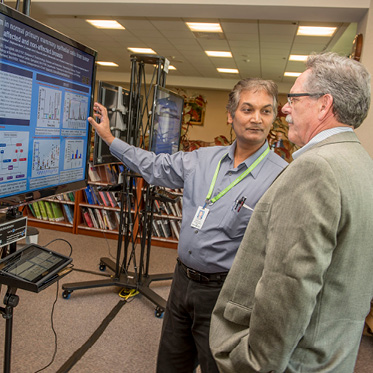 two individuals discussing a graph on a digital touch screen