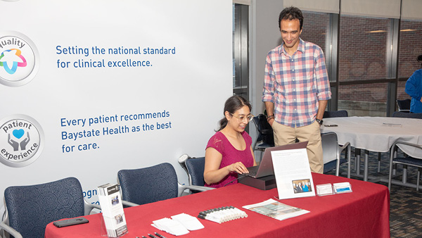 two individuals at a booth at a conference