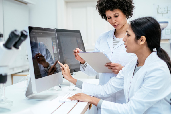 two researchers looking over data on a computer screen
